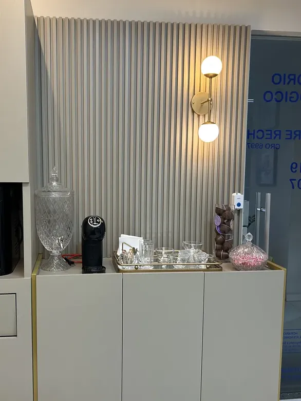 Canto com cafeteira, xícaras de cristal e balas, ao lado da porta do consultório