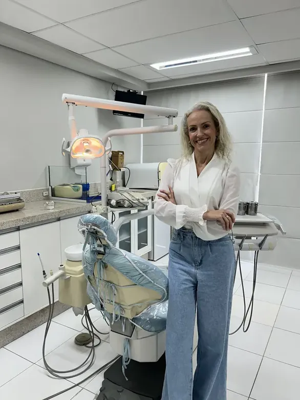 Dra. Jossemare Rech em pé ao lado da cadeira, na sala onde atende