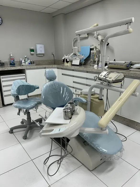 Sala clínica vista de dentro, com a cadeira, o mocho e a bancada de instrumentos
