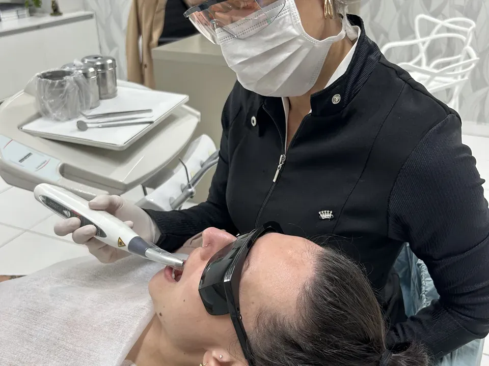 Dra. Jossemare Rech aplica laser de baixa potência em uma paciente, as duas com óculos de proteção